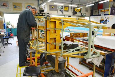 Een vrijwilliger-expert van de Brussels Air Museum Restoration Society aan het werk aan de romp van een vliegtuig