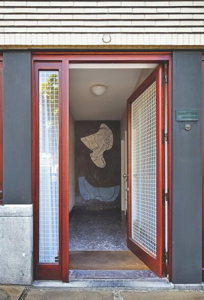 De ingang van het architectenbureau in Stynens eigen woning aan de Camille Huysmanslaan in Antwerpen, met muurschildering van René Guiette