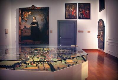 De maquette van de stad omstreeks 1667 met op de achtergrond het portret van Maria van Hongarije, rond 1636 geschilderd door Jasper Beckx