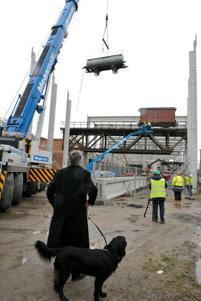 Treinwagons krijgen een plaats op de spoorwegbrug over de Maas die in 2013 van Namen is overgebracht. François Schuiten, op wandel met de hond, komt een kijkje nemen, Train World,