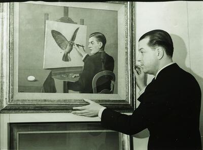 E.L.T. Mesens poserend voor ‘La Clairvoyance’ van René Magritte in de London Gallery, Londen, januari 1937 archief voor hedendaagse kunst in belgië - koninklijke musea voor schone kunsten van belgië, brussel, surrealisme,